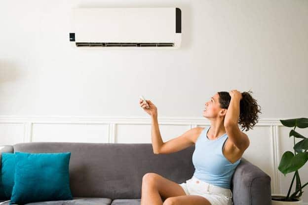 Alt Text: A lady adjusting the AC temperature and seems frustrated