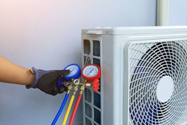 View of a hand wearing a glove and checking the refrigerant levels of AC