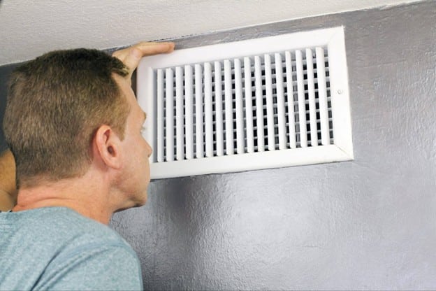 a male inspecting air vents