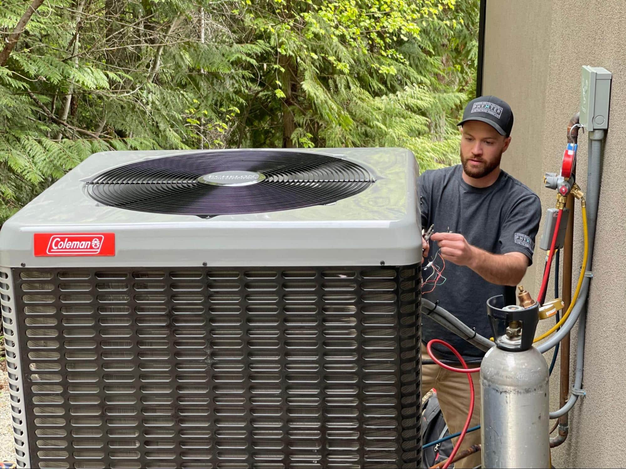 A view of a HVAC technician standing next to a heat pump 