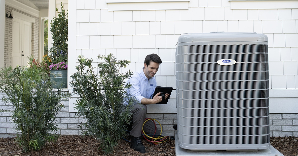A person checking the function of AC coils outside of the home