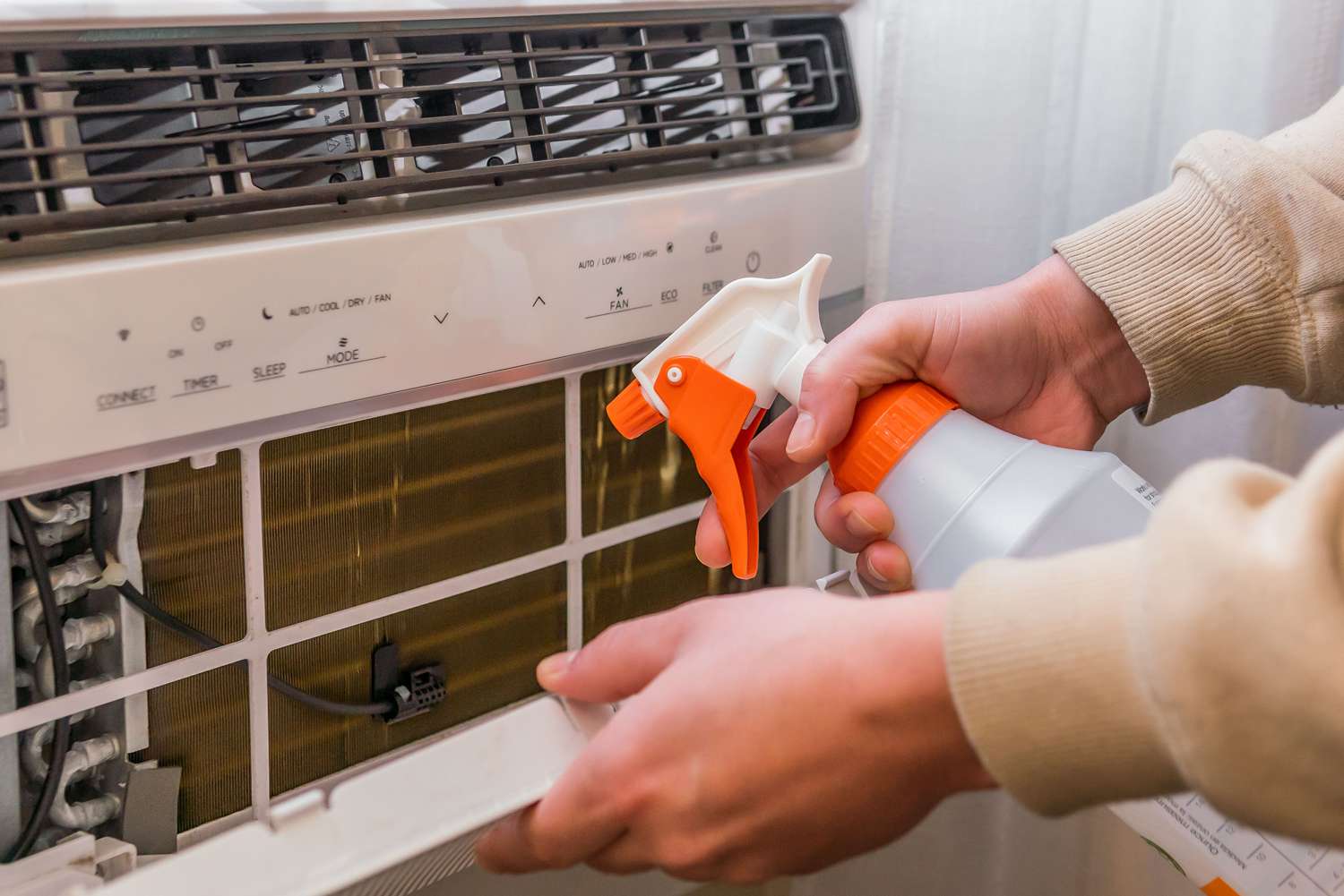 A view of spraying cleaner inside a window AC unit