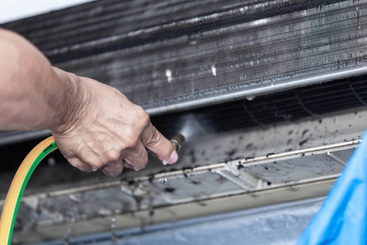 close-up of a hand cleaning condenser coils